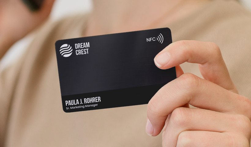 Black NFC business card held in hand.